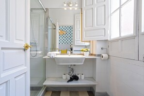 A bathroom with a white sink, a mirror, a shower, and a toilet. - Genteel Home Galera II (Seville)