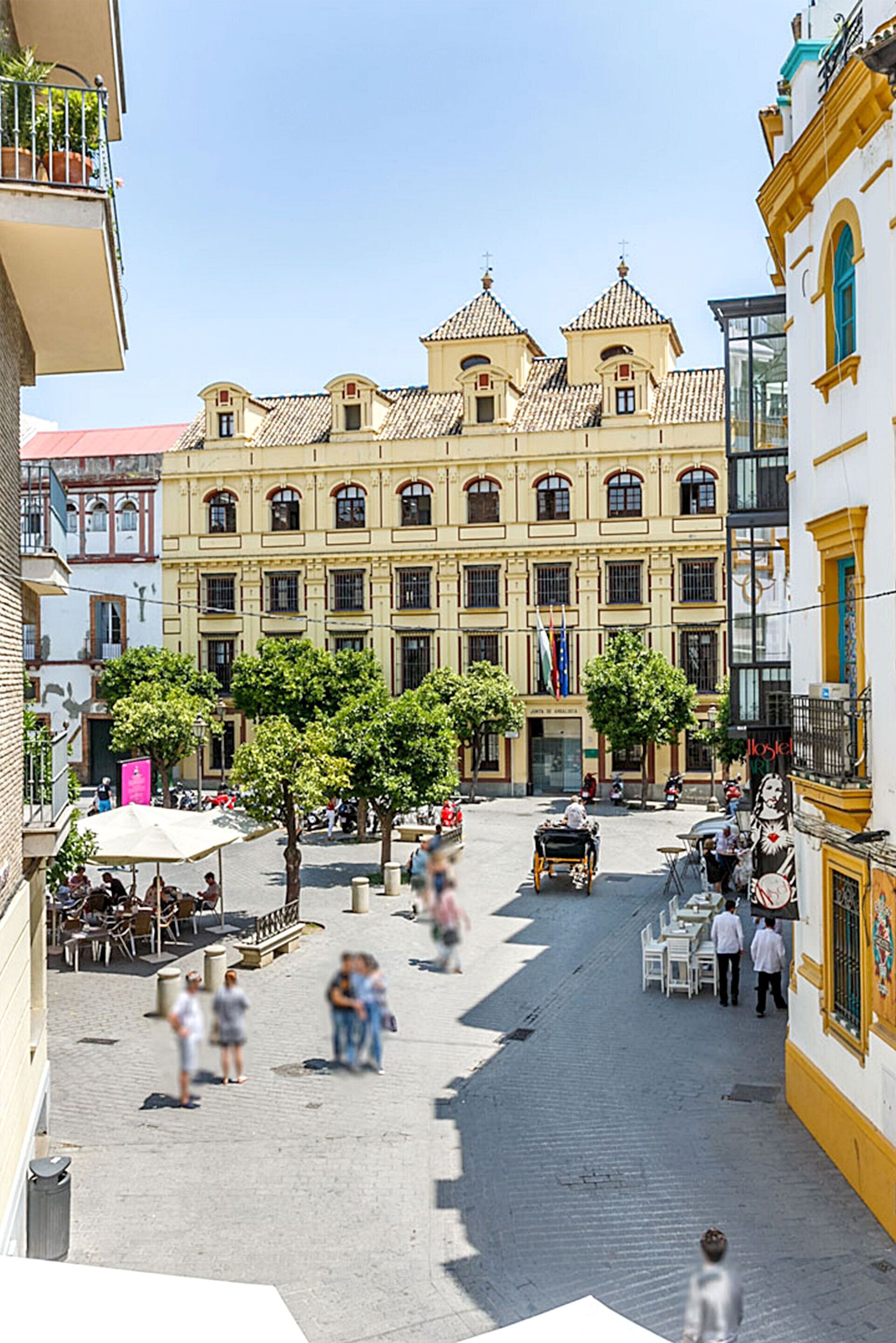 A historic building with a central courtyard, surrounded by trees and outdoor seating areas.