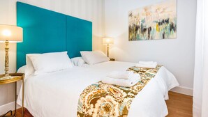 A hotel room with a bed, two bedside lamps, a painting on the wall, and a window with curtains. - Genteel Home San Gregorio (Seville)