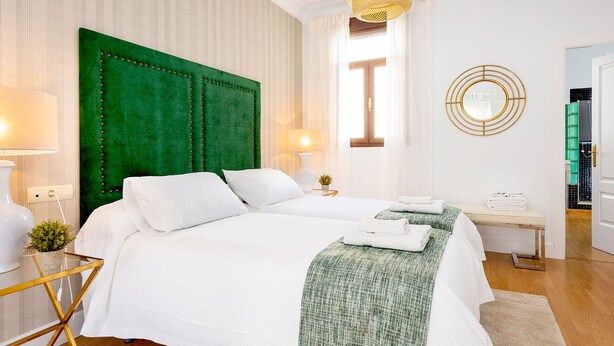 Una camera d'hotel con un letto grande, un comodino, una lampada, uno specchio e vista sull'esterno.