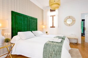 Ein Hotelzimmer mit einem großen Bett, einem Nachttisch, einer Lampe, einem Spiegel und Blick ins Freie.