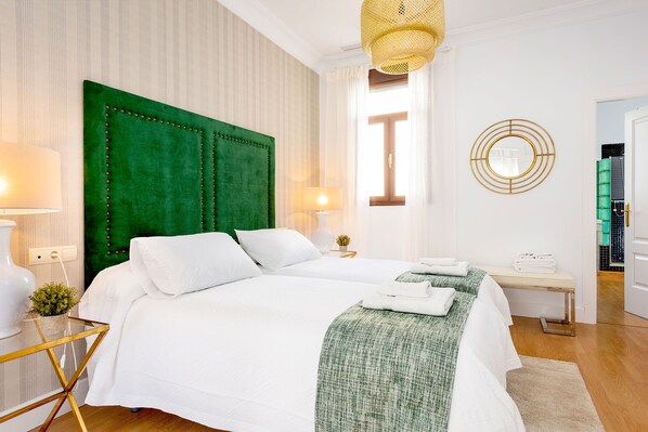 A hotel room with a large bed, a bedside table, a lamp, a mirror, and a view of the outside. - Genteel Home San Gregorio (Seville)