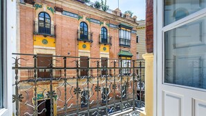 Un edificio con facciata in mattoni, ringhiere in ferro battuto decorate e una porta bianca.