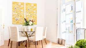 Un'area pranzo con un tavolo in vetro, sedie bianche e un vaso con fiori.