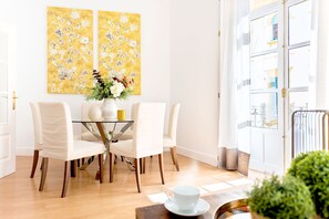 A dining area with a glass table, white chairs, and a vase with flowers. - Genteel Home San Gregorio (Seville)