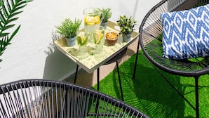 Eine Dachterrasse mit Tisch für zwei Personen, ausgestattet mit Getränken und Snacks, mit Blick auf eine Stadtlandschaft und einem markanten Kirchturm.