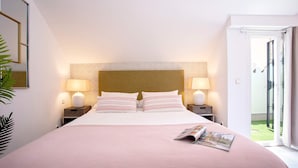Ein ordentlich bezogenes Bett mit einer rosa Bettdecke, zwei Nachttischlampen und einer Zeitschrift auf dem Bett.