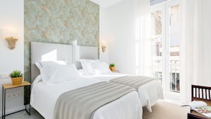 A hotel room with a large bed, two bedside tables with lamps, a view of the outside balcony, and a textured wall. - Genteel Home Encarnacion (Seville)