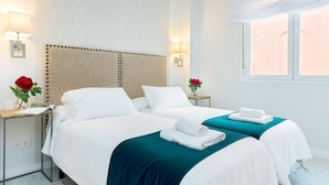 A hotel room with two beds, a nightstand, a lamp, and a window with a view. - Genteel Home Encarnacion (Seville)