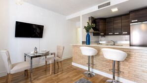 A modern kitchen with dark wood cabinets, a stainless steel refrigerator, and a bar area with white stools. - Genteel Home Francos VII (Seville)