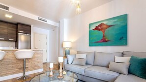 A modern living room with a glass coffee table, a grey sofa, and a painting on the wall. - Genteel Home Francos VII (Seville)