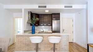 A modern kitchen with a central island, two bar stools, and a blue vase. - Genteel Home Francos VII (Seville)