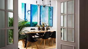 A dining area with a wooden table, black chairs, and a large painting on the wall. - Genteel Home Casa Alhóndiga Terrace (Seville)
