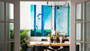 An open-plan dining area with a wooden table, black chairs, and a large abstract painting on the wall. - Genteel Home Casa Alhóndiga Terrace (Seville)