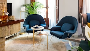 A modern living room with a round rug, two blue armchairs, a coffee table, and a large plant. - Genteel Home Casa Alhóndiga Terrace (Seville)