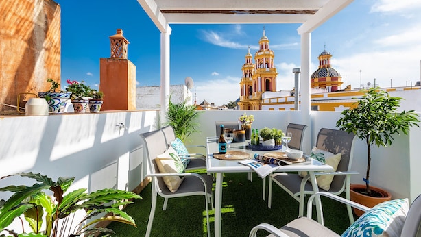 An outdoor patio with a table set for dining, surrounded by chairs and potted plants. - Genteel Home Casa Alhóndiga Terrace (Seville)