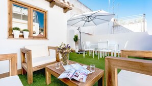 An outdoor seating area with wooden furniture, a table with magazines, and a white umbrella. - Genteel Home Galera Terrace (Seville)