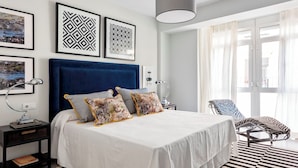 A modern bedroom with a large bed, a blue headboard, and a black and white striped rug. - Genteel Home Albareda (Seville)