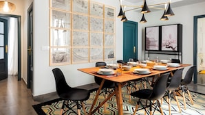 A dining area with a wooden table set for six, black chairs, and a patterned rug. - Genteel Home Albareda (Seville)