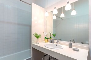A modern bathroom with a white sink, mirror, and three pendant lights. There are potted plants on the counter. - Genteel Home Larios (Málaga)