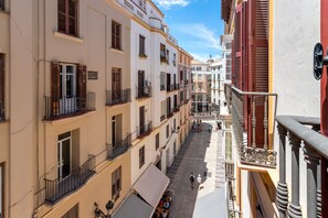 A narrow street with buildings on either side, featuring balconies with railings and windows with shutters. - Genteel Home Larios (Málaga)
