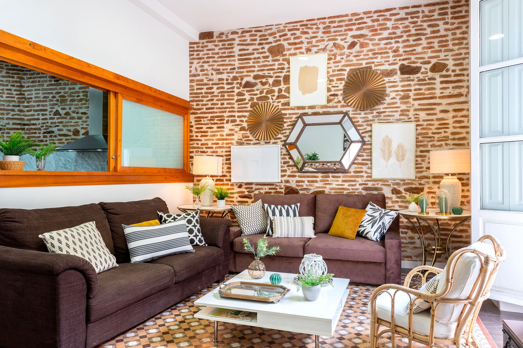 A living room with a stone wall, two sofas, a coffee table, and wicker chairs.