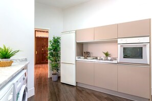 Une cuisine moderne équipée d’un four encastré, d’une machine à café et d’une plante en pot.