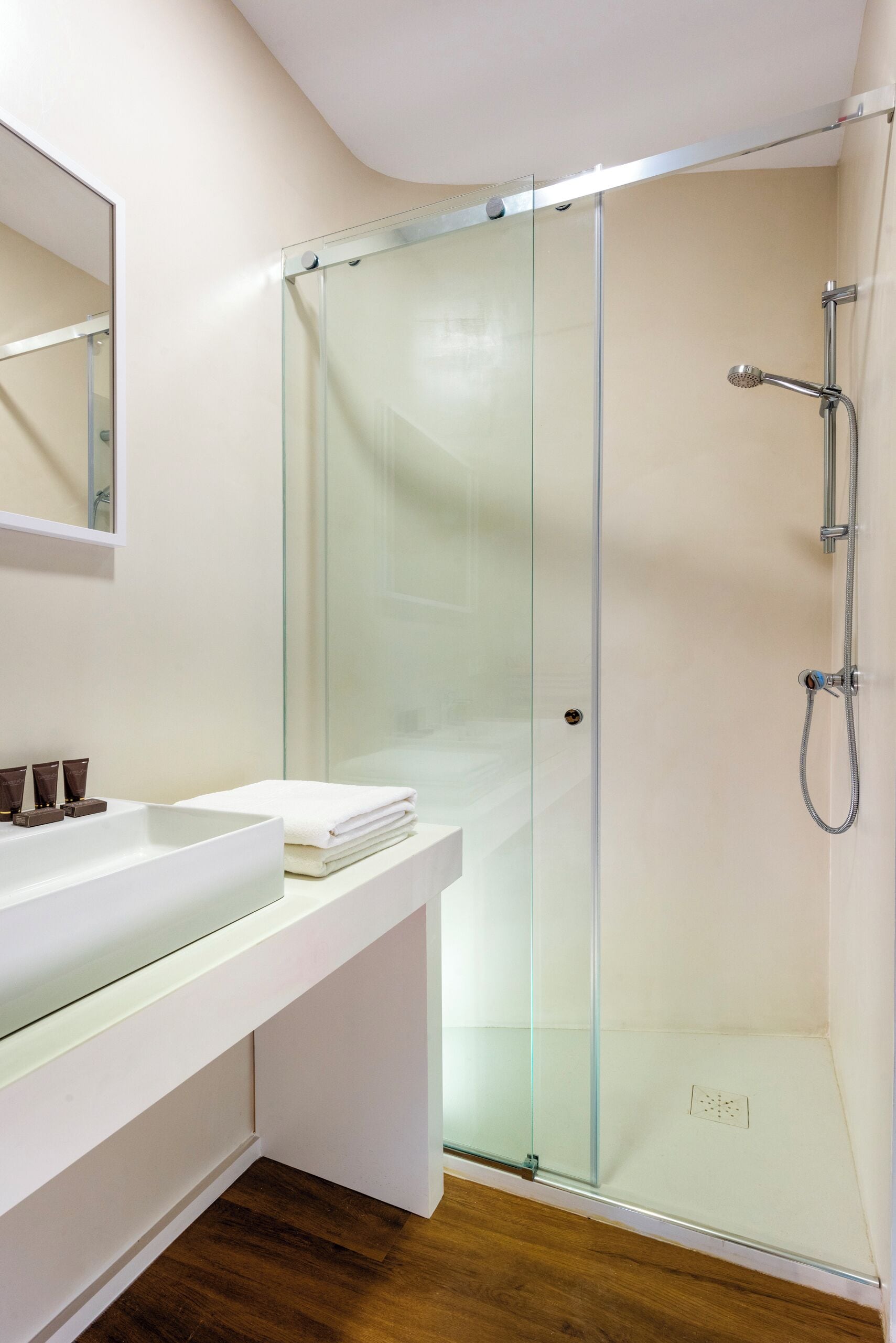 Une salle de bain moderne avec une douche à parois de verre, un meuble-lavabo blanc et un miroir au-dessus du meuble.
