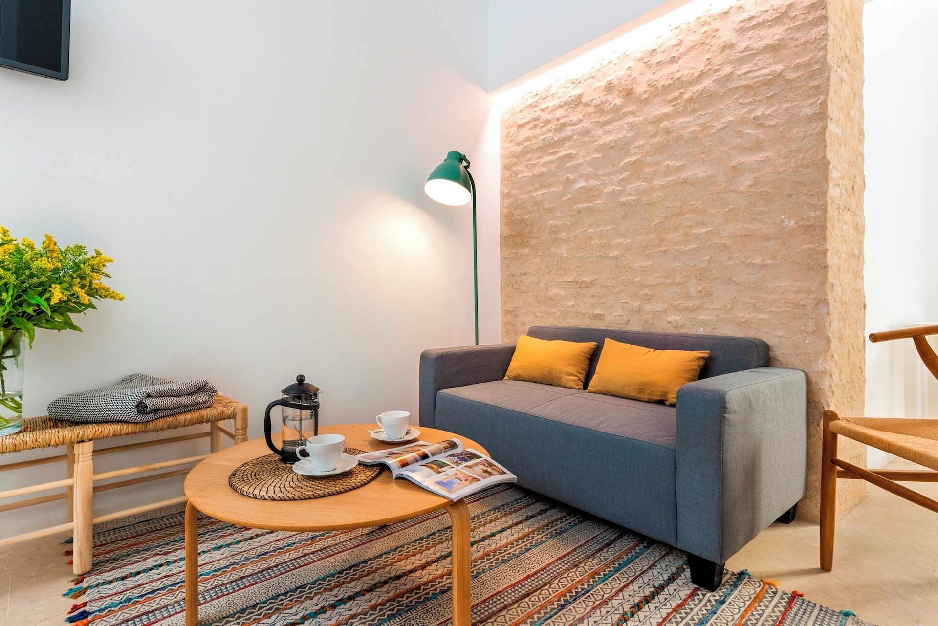 Una sala de estar acogedora con un sofá, una mesa de centro, una lámpara y una revista.