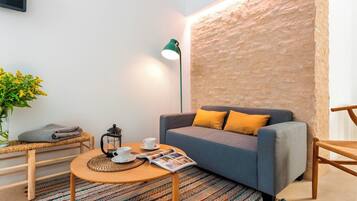 Una sala de estar acogedora con un sofá, una mesa de centro, una lámpara y una revista.