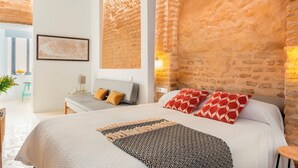 A modern bedroom with a large bed, a desk, and a chair. There is a window with a view of the outdoors. - Genteel Home Santa Teresa (Seville)