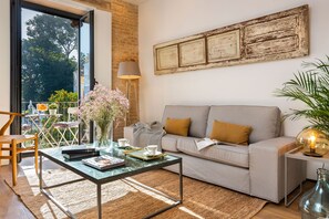 Een woonkamer met een bank, salontafel en uitzicht op de omgeving.