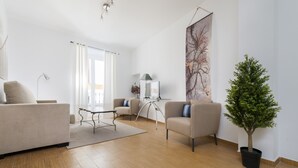 A modern living room with a sofa, armchairs, a coffee table, and a potted plant. - Genteel Home Don Pelayo (Seville)