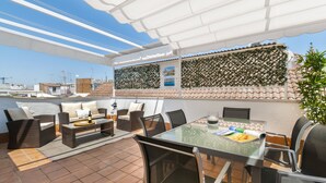 A rooftop terrace with outdoor furniture, a glass table, and a view of the cityscape. - Genteel Home Don Pelayo (Seville)