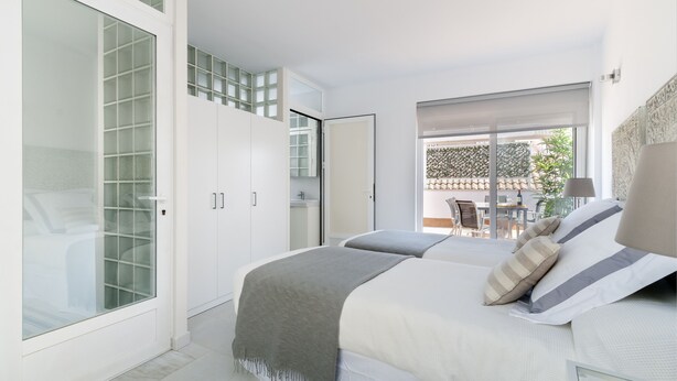 A bedroom with a bed, a wardrobe, and a sliding glass door leading to a balcony. - Genteel Home Don Pelayo (Seville)