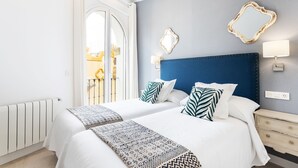 A hotel room with a large bed, a blue headboard, two bedside tables, a mirror, and a view of the outside balcony. - Genteel Home Mateos Gago IV (Seville)