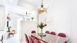 A modern dining area with a glass table, red upholstered chairs, and a hanging light fixture. - Genteel Home Mateos Gago IV (Seville)