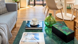 Un salon moderne comprenant un canapé, une table basse, une table à manger avec des chaises, une plante en pot et une vue à travers une porte vitrée.