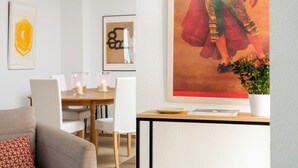 A modern living room with a sofa, a dining table with chairs, and a poster on the wall. - Genteel Home Conde de Ibarra (Seville)
