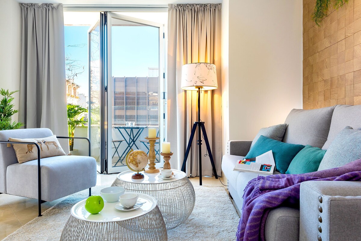 A modern living room with a grey sofa, a round coffee table with a globe and candles, and a floor lamp.