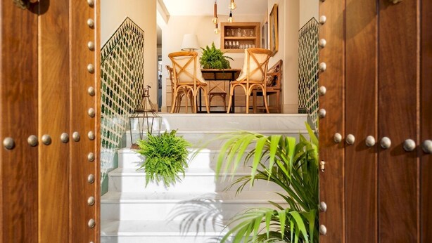 A staircase leading to a dining area with a chandelier, wooden doors, and potted plants. - Genteel Home Carmen San Ignacio I (Granada)