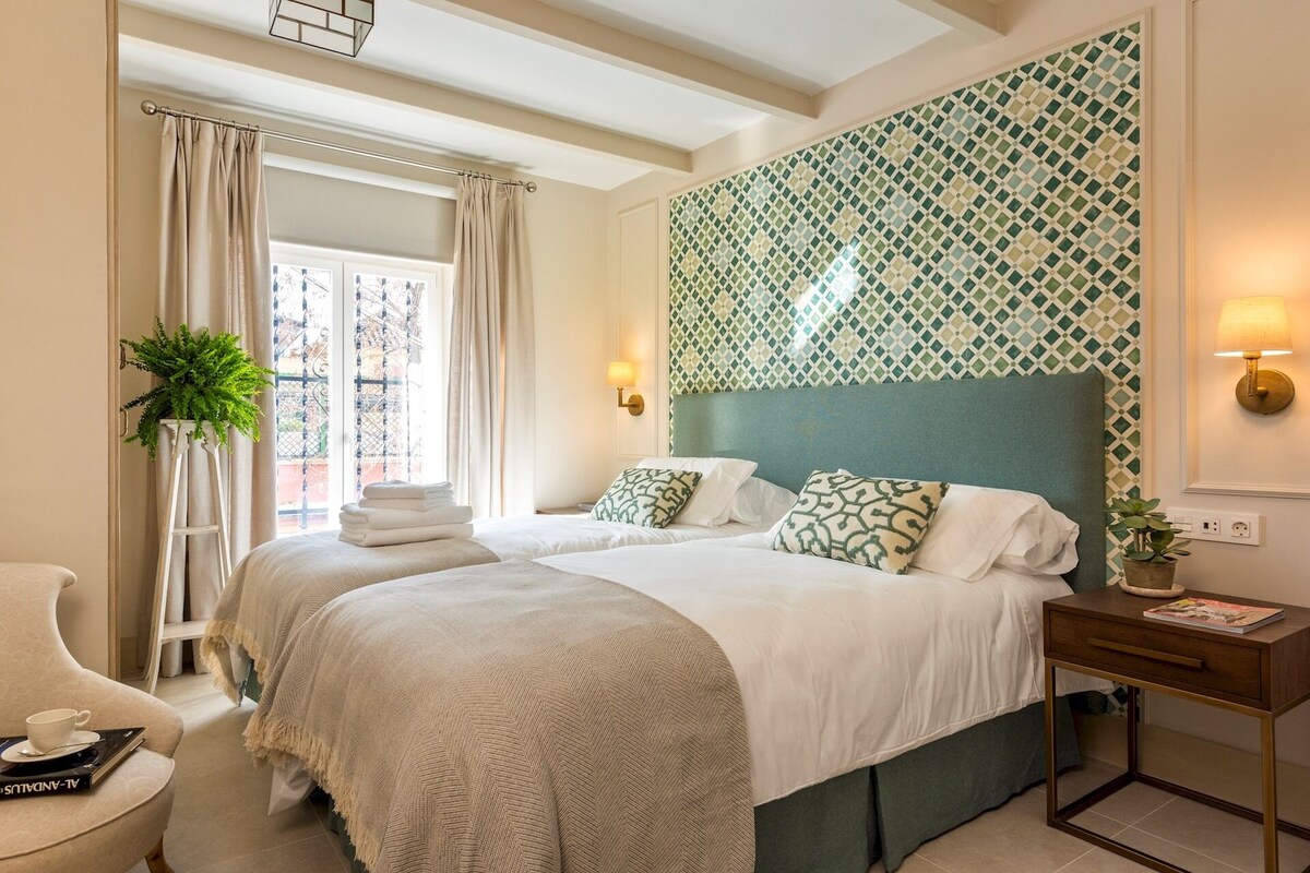 Une chambre d’hôtel avec un grand lit, un bureau avec une lampe et une vue sur l’extérieur par une fenêtre avec des rideaux.