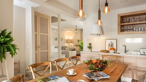 A modern kitchen with wooden cabinets, a dining table with chairs, and pendant lighting. - Genteel Home Carmen San Ignacio I (Granada)