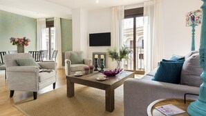 A living room with a sofa, armchairs, a coffee table, and a TV mounted on the wall. - Genteel Home Cabildo III (Seville)