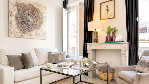 A living room with a white sofa, a glass coffee table, a fireplace, and a painting on the wall. - Genteel Home Galera III (Seville)