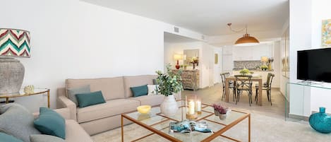 A modern living room with a sofa, coffee table, and dining area.