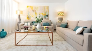 A living room with a beige sofa, a coffee table, and a painting on the wall. - Genteel Home Plaza de las Flores (Málaga)