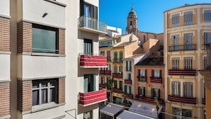 Un edifici d'àmbit múltiples pisos amb balcons, una torre d'església i un café amb terrassa.
