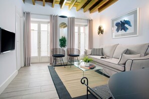 A modern living room with a sofa, two chairs, a coffee table, a TV, and a large window with curtains. - Genteel Home Padre Marchena (Seville)