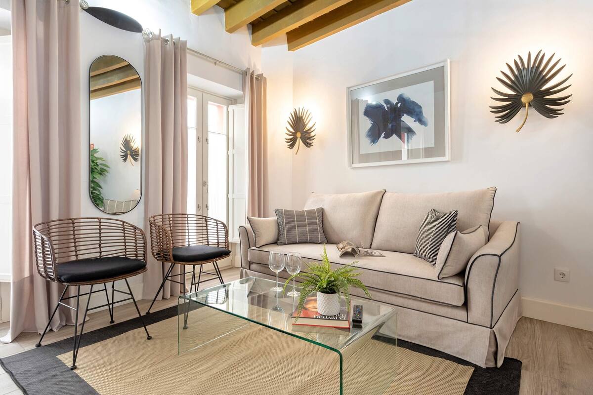 A living room with a sofa, two chairs, a coffee table, a mirror, and decorative wall art.